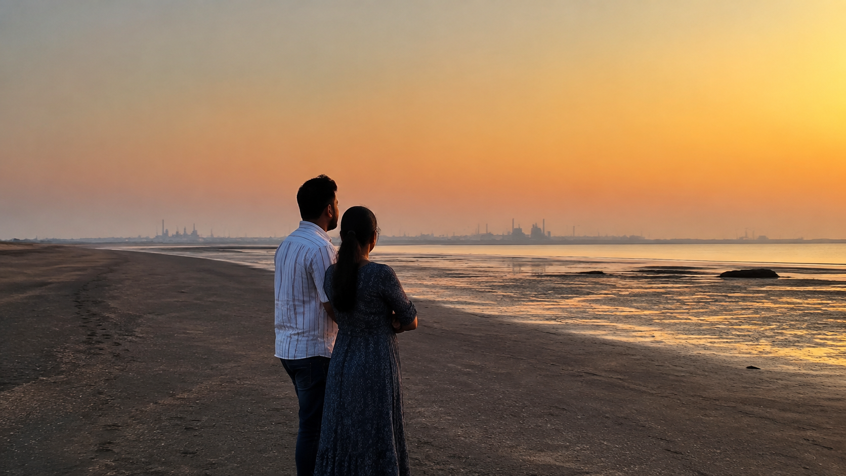 Couple watching sunset on the dark tidal shore at Suvali Beach near Surat